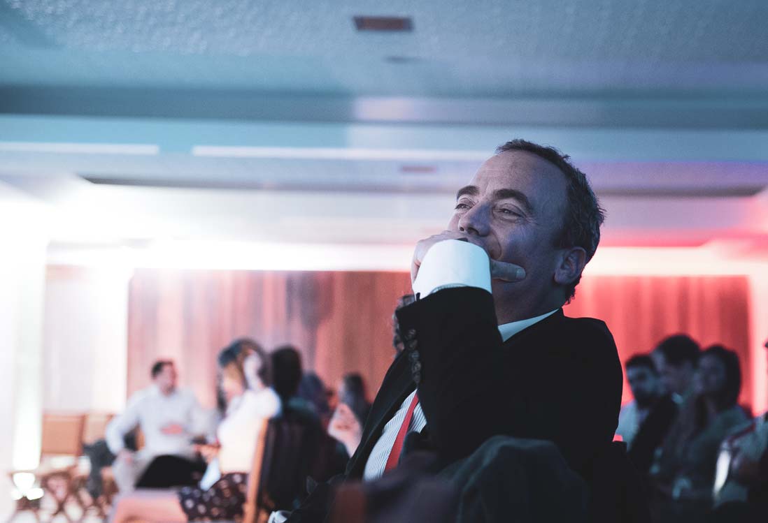 Pedro Fonseca sorrindo, sentado na plateia de um evento