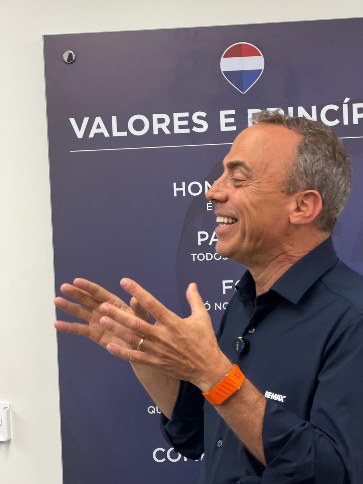 Pedro Fonseca falando e rindo, diante do painel Valores e Princípios da RE/MAX